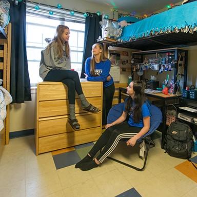 Three U N E students chatting in their dorm room